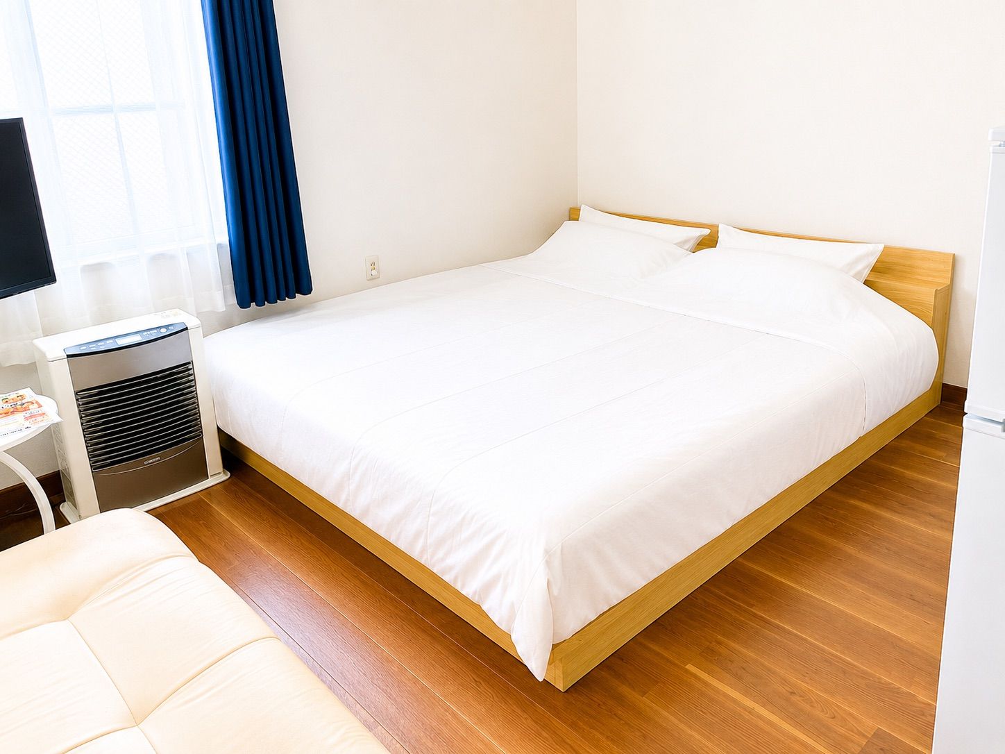 Een hotelkamer met een enkel bed, nachtkastje, lamp en een verwarming.