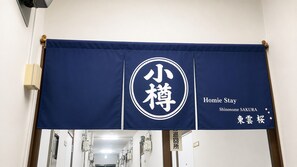 A banner with Japanese characters and English text indicating a hotel named 'Homie Stay Shinonome SAKURA' with a sign for the reception. - New Listing (小樽市)