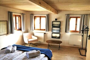 Une chambre d’hôtel avec un lit, une chaise, une petite table et un radiateur.