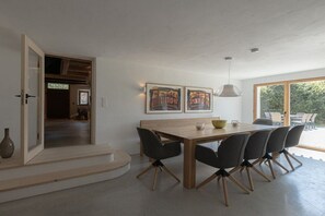 A modern dining area with a wooden table and chairs, a pendant light, and artwork on the wall. - Holiday home in Reit im Winkl with balcony (Reit im Winkl)