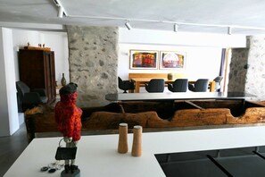 Ein moderner Konferenzraum mit einem weißen Tisch, schwarzen Stühlen und einer Steinwand.