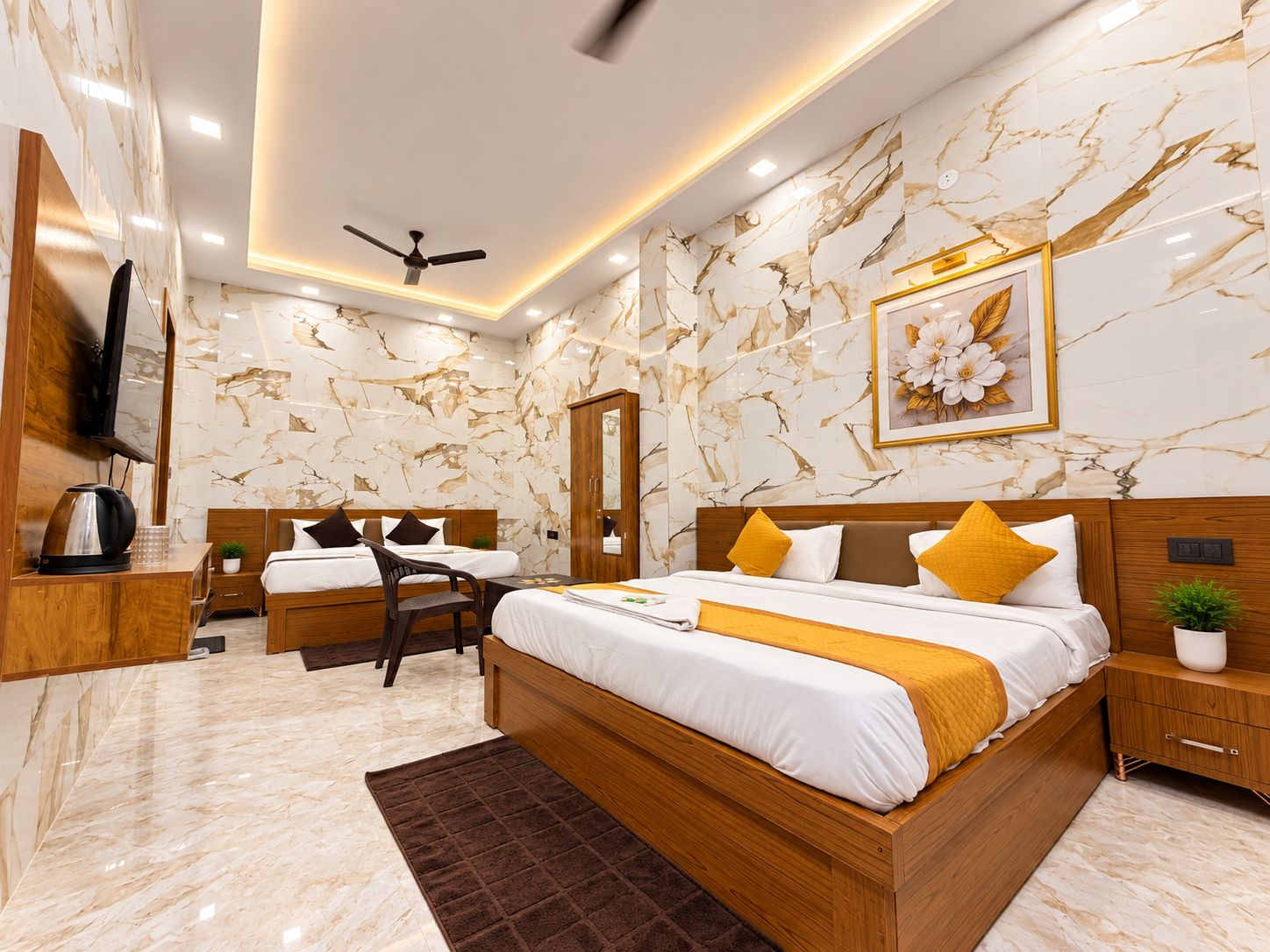 A modern bedroom with a large bed, two smaller beds, a desk, a TV, and a ceiling fan.