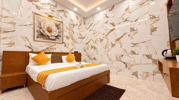 A modern bedroom with a wooden bed, marble-patterned walls, a ceiling fan, and a framed floral artwork.
