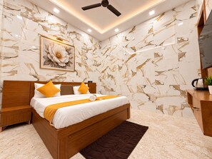 Un dormitorio moderno con una cama de madera, paredes con diseño de mármol, un ventilador de techo y una obra de arte floral enmarcada.