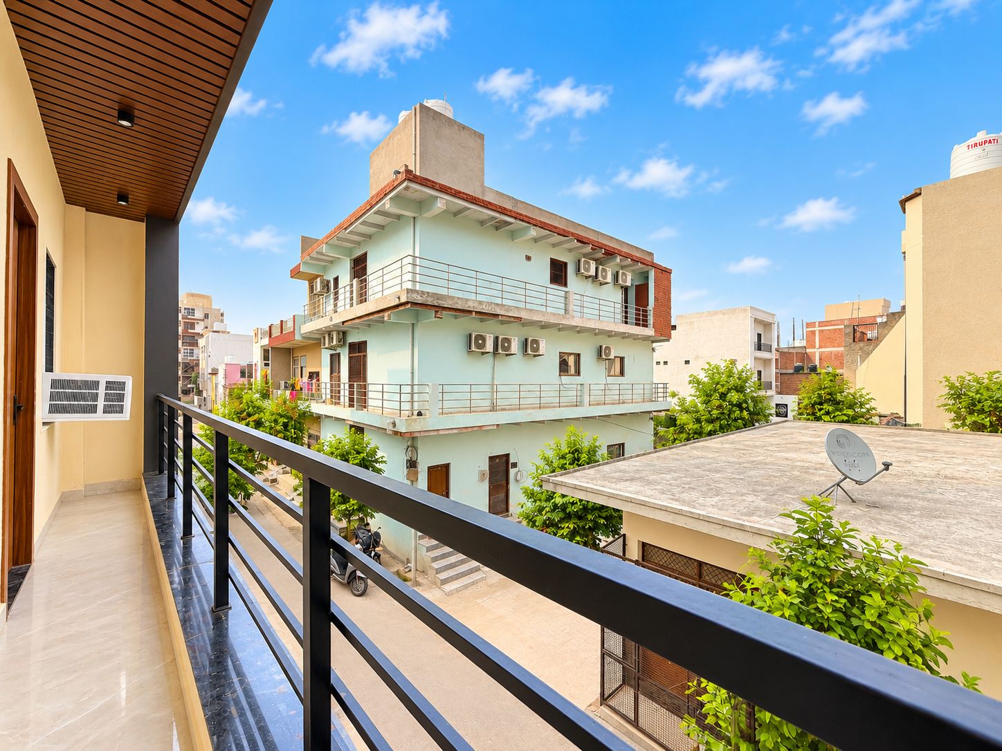 A multi-story residential building with balconies, air conditioning units, and a satellite dish.