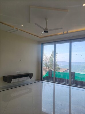 A spacious room with a large window, a ceiling fan, and a bench. - Beautiful 3-bedroom bungalow with AC in serene Panchgani (Panchgani, Satara)