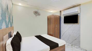 A hotel room with a bed, a wardrobe, an air conditioning unit, and a television.