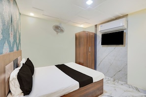 Ein Hotelzimmer mit einem Bett, einem Kleiderschrank, einer Klimaanlage und einem Fernseher.
