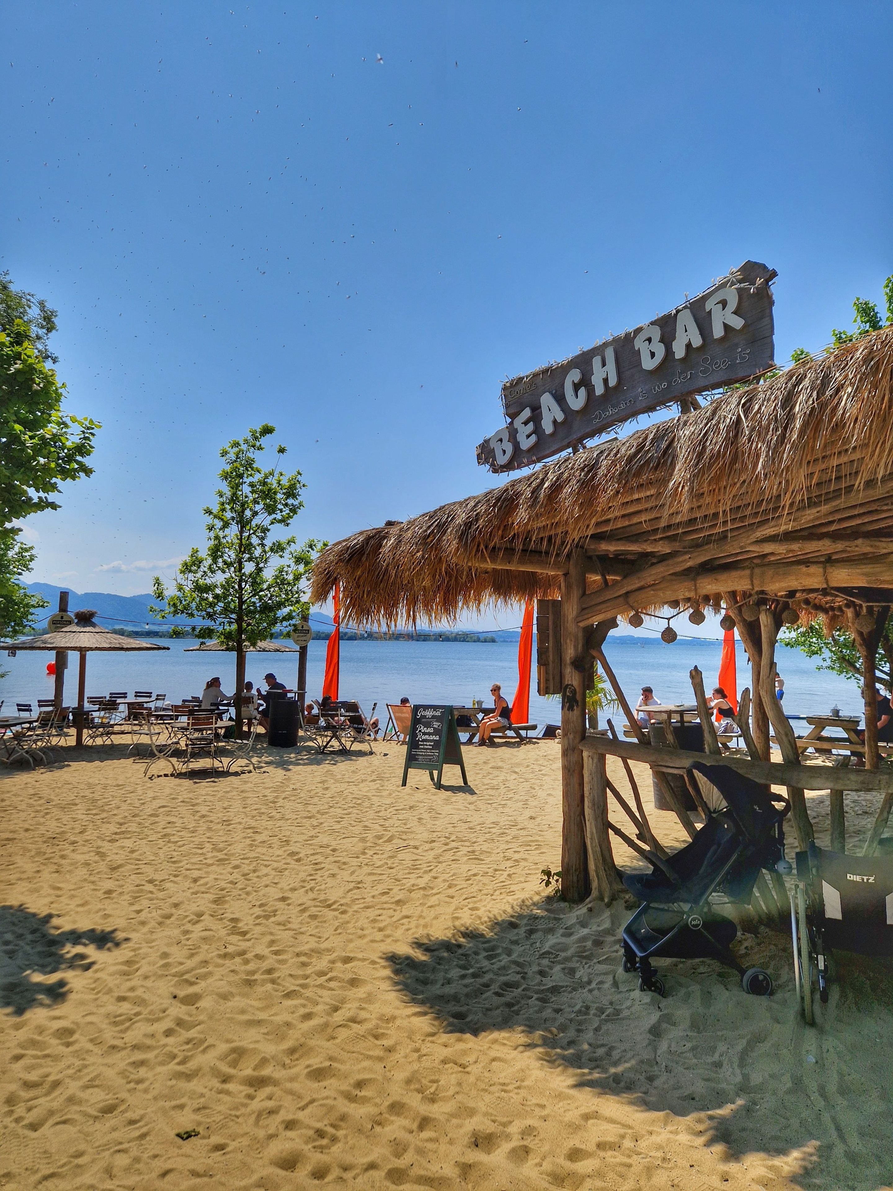 Een strandbar met rieten dak, terras en uitzicht op zee.