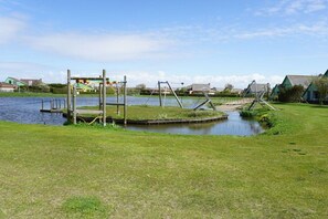 A park with a small pond, swings, and a wooden structure. - Apartment with 1 bedroom (Julianadorp aan Zee)