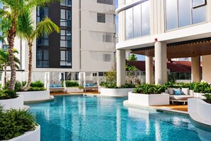 A modern hotel with a swimming pool, outdoor seating, and lush greenery. - Elevated Escape at Sunrise - Lagoon Main Beach (Main Beach)