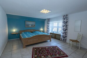 A bedroom with a bed, a nightstand, a chair, a window with curtains, and a radiator. - Holiday apartment in Issum with swimming pool (Issum)