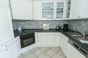A kitchen with white cabinets, a black countertop, a coffee maker, and a sink. - Holiday apartment in Issum with swimming pool (Issum)