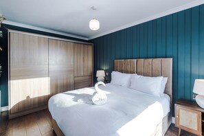 Ein Schlafzimmer mit Bett, Nachttisch, Lampe und Kleiderschrank.