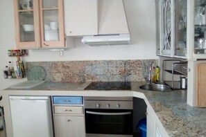A compact kitchen with a dishwasher, oven, and a microwave. There are cabinets with glass doors and a countertop with a sink. - Holiday apartment in Lagos with swimming pool (Lagos)