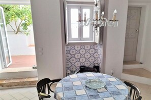 A dining area with a table set for two, a chandelier, and a patterned wall. - Holiday apartment in Lagos with swimming pool (Lagos)