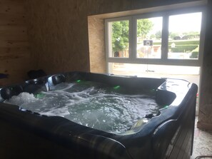 A hot tub in a room with wooden walls and a window. - Holiday Home 'La Régordane' with Mountain View, Pool and Spa in Solignac-sur-Loire (Solignac-sur-Loire)