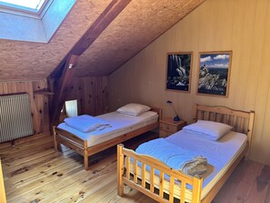 A cozy attic bedroom with two wooden beds, a skylight, and two framed pictures on the wall. - Holiday Home 'La Régordane' with Mountain View, Pool and Spa in Solignac-sur-Loire (Solignac-sur-Loire)