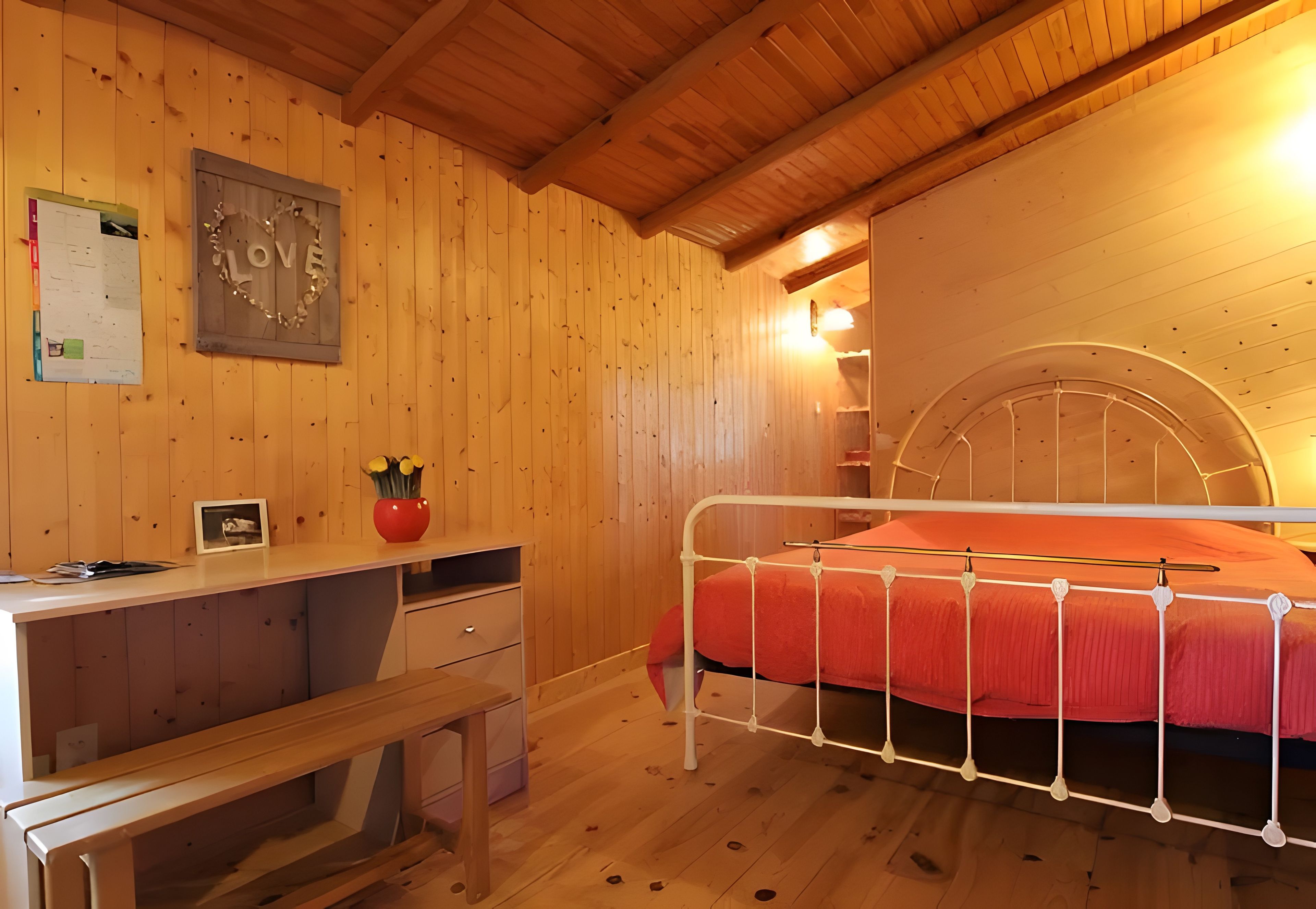 A wooden room with a bed, a desk, and a chair.