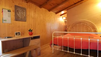 A wooden room with a bed, a desk, and a chair.