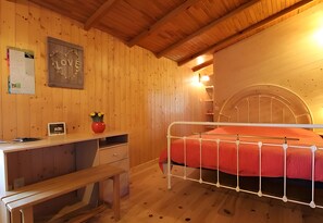 Una habitación de madera con una cama, un escritorio y una silla.