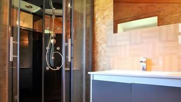 Un baño moderno con ducha acristalada, techo de madera y lavamanos empotrado con armarios.