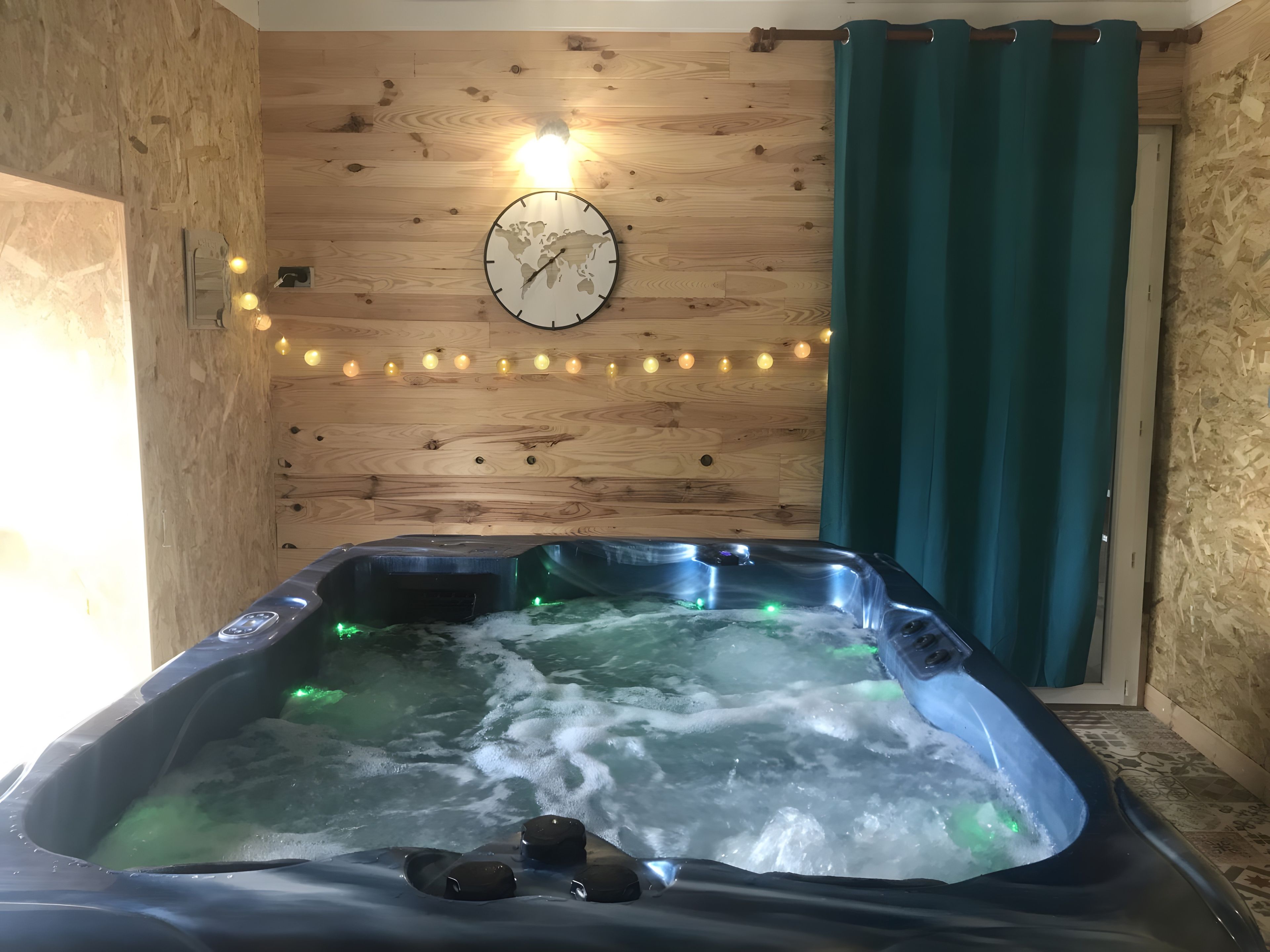 A hot tub with water jets, a clock on the wall, and string lights.