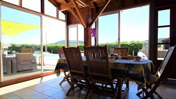 A dining area with a table, chairs, and a view of a swimming pool and greenery.