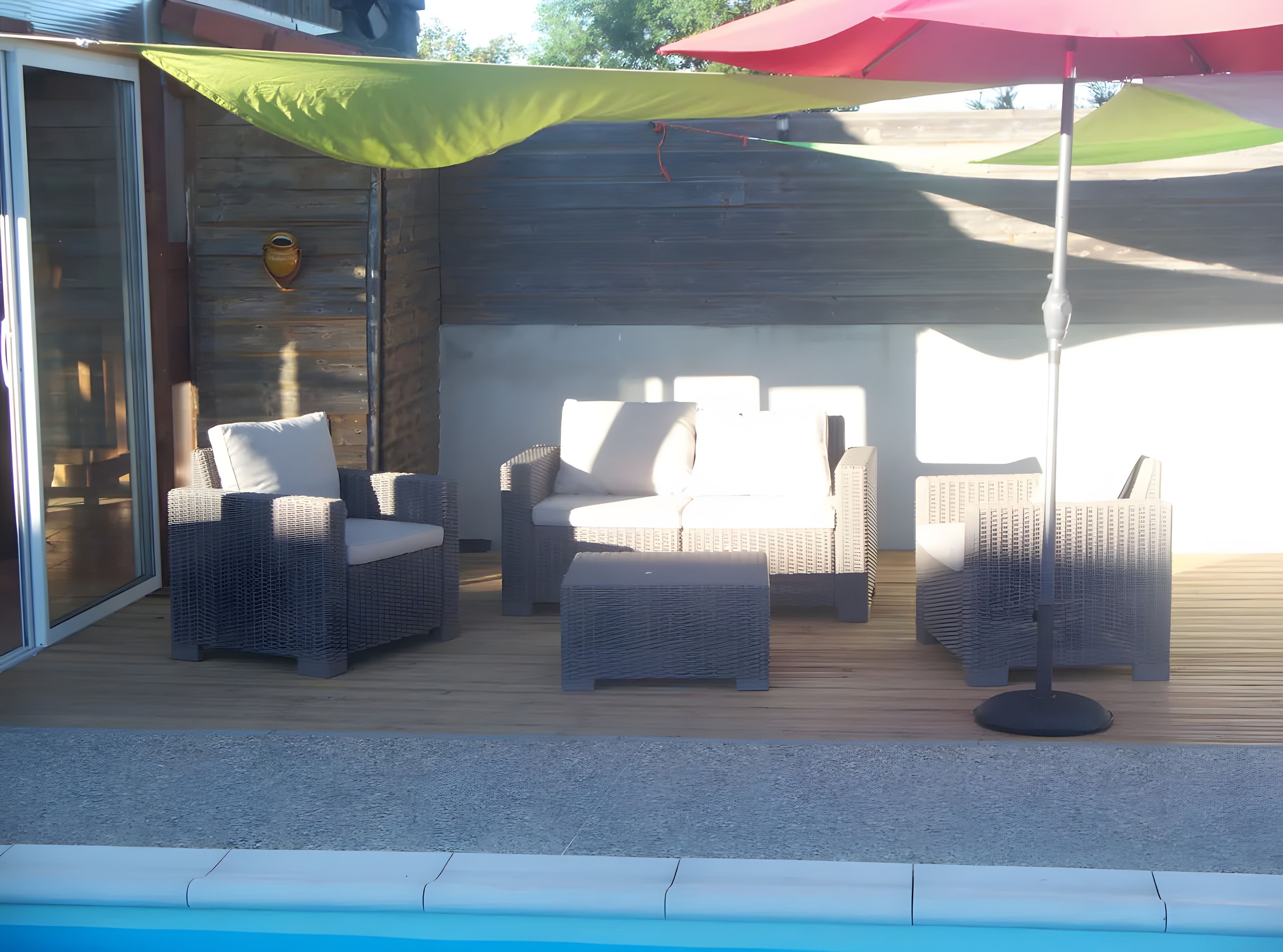 Un espace extérieur aménagé avec des meubles en osier et une piscine.
