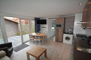 A compact kitchen with a dining area, a washing machine, and a TV. - Noordkerkepad Westkapelle (Westkapelle)