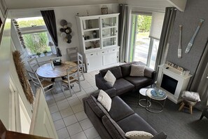 A living room with a sofa set, a dining table, and a cabinet. - Holiday home with 3 bedrooms (Julianadorp)