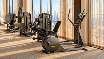 Een sportschool met cardio-apparatuur en gewichten, grote ramen met uitzicht op de stad.