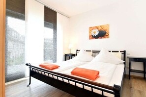 A hotel room with a bed, a nightstand, a lamp, and a window with a view. - Holiday apartment with 1 bedroom (Lindau)