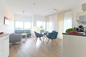 A modern kitchen with a dining area, large windows, and a view of greenery. - Holiday apartment with 1 bedroom (Lindau)