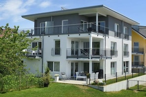 A multi-story residential building with balconies, a covered outdoor seating area, and a well-maintained lawn. - Holiday apartment with 1 bedroom (Lindau)