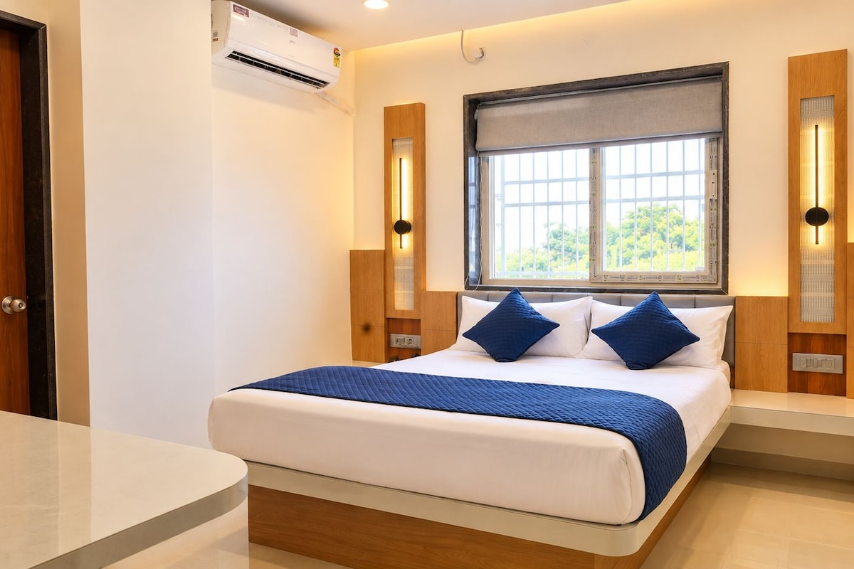 A modern bedroom with a bed, bedside tables, a window, and an air conditioning unit.