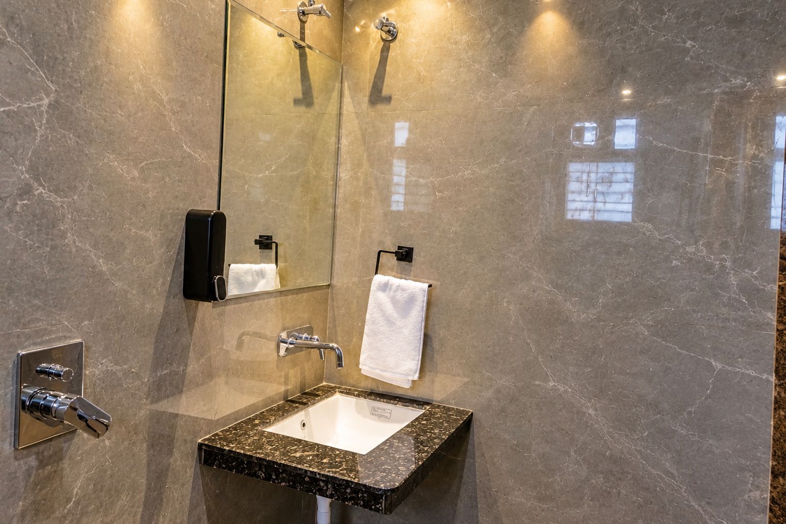 A bathroom with a marble sink, a mirror, a towel rack, and a handheld showerhead.