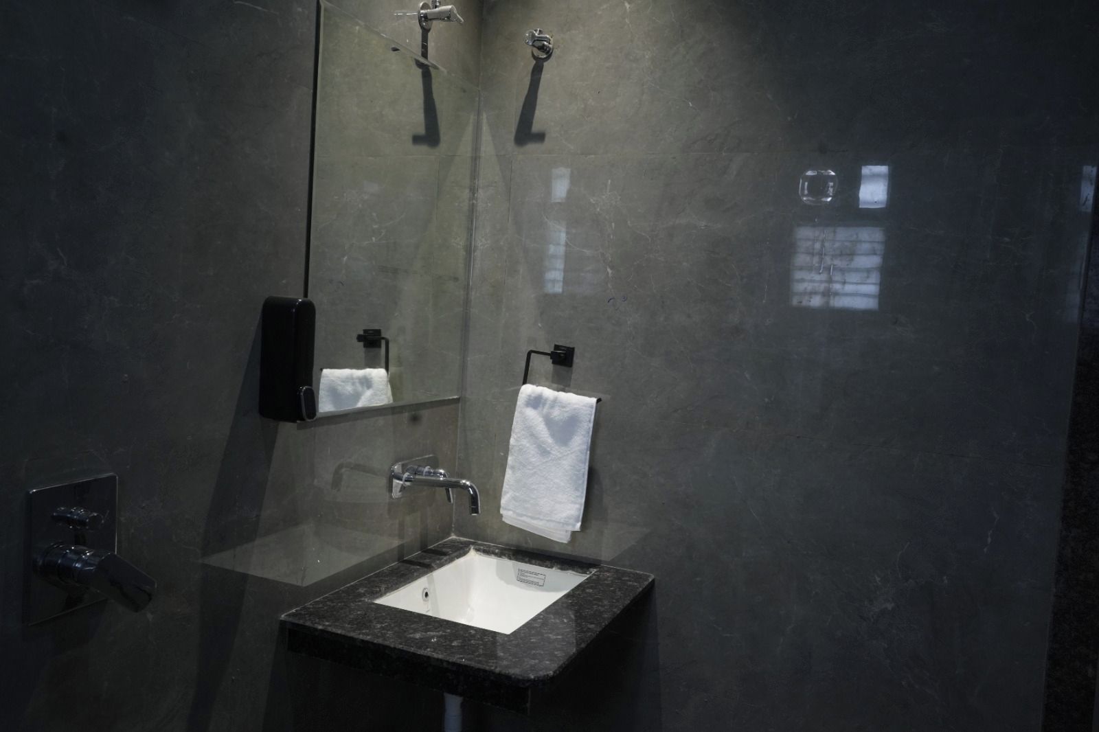 A modern bathroom with a glass-enclosed sink, a mirror, and a towel rack.