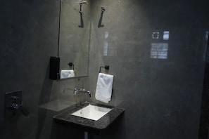 A modern bathroom with a glass-enclosed sink, a mirror, and a towel rack. - Urban 24 Inn (Latur)