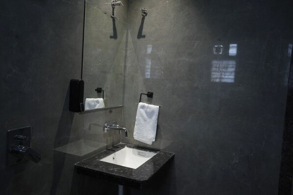 A modern bathroom with a glass-enclosed sink, a mirror, and a towel rack.