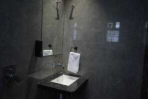 Casa de banho moderna com lavatório com divisória de vidro, espelho e porta-toalhas.