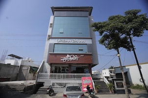 Um edifício de vários andares com uma placa indicando 'URBAN 24 INN' e uma entrada visível com degraus.