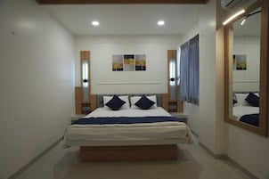 Quarto com cama, mesas de cabeceira, espelho e obras de arte na parede.