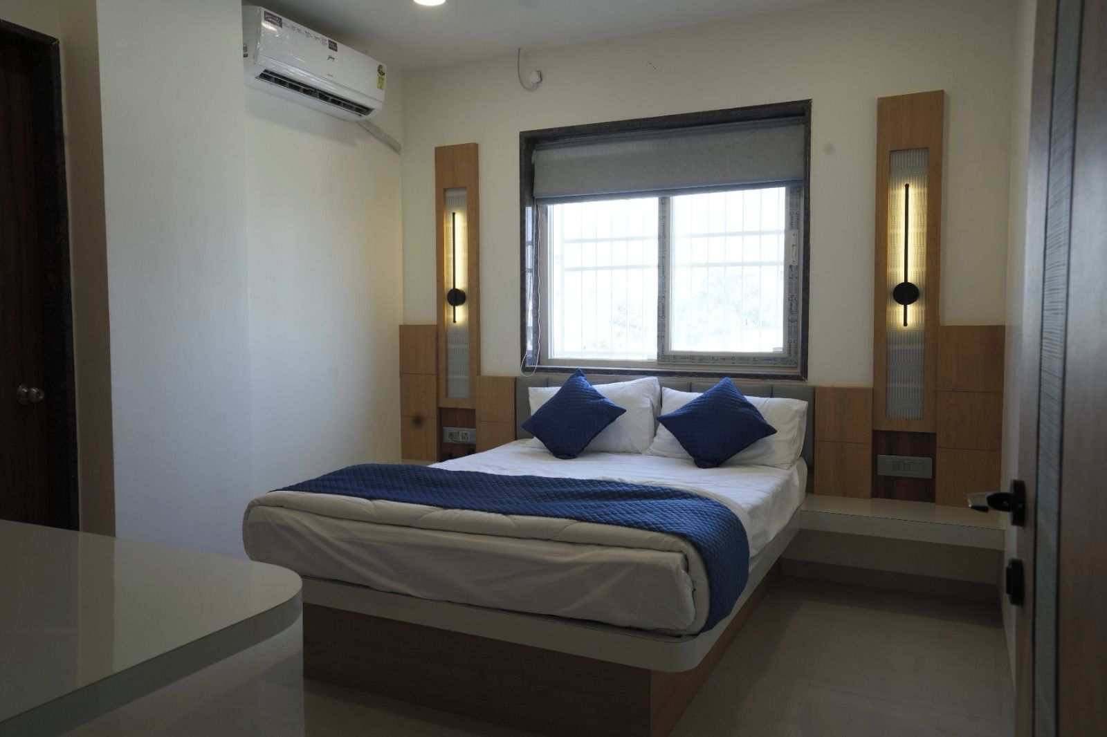 Een slaapkamer met een bed, nachtkastjes, een raam en een airconditioning.