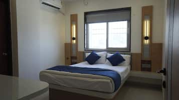 Een slaapkamer met een bed, nachtkastjes, een raam en een airconditioning.