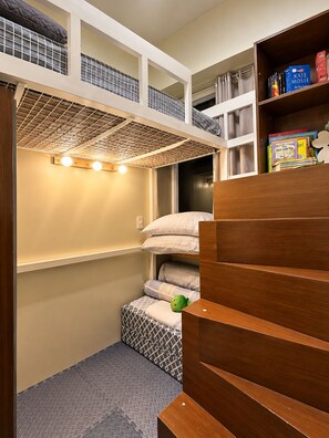 A compact room with a bunk bed, a bookshelf with books, and a small seating area with cushions. - Boho Family Suite 3BR 2bath 2Balcony in St. Lukes QC Manila PH (Quezon City)