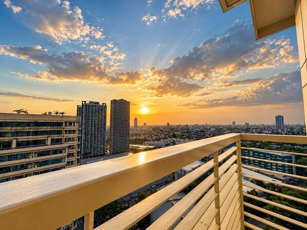 A balcony with a view of a cityscape during sunset.