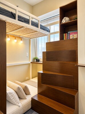 A room with a bunk bed, a wooden staircase, a bookshelf with books, and a window with natural light. - Boho Family Suite 3BR 2bath 2Balcony in St. Lukes QC Manila PH (Quezon City)