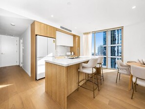 Una cocina moderna con una isla central, taburetes de bar y un comedor con mesa y sillas.