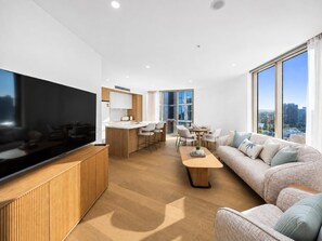 Una sala moderna con televisor de pantalla plana, un sofá, una mesa de centro y un comedor con sillas y una mesa.